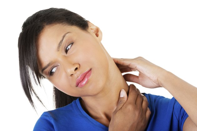 Young woman holding hand on her neck.