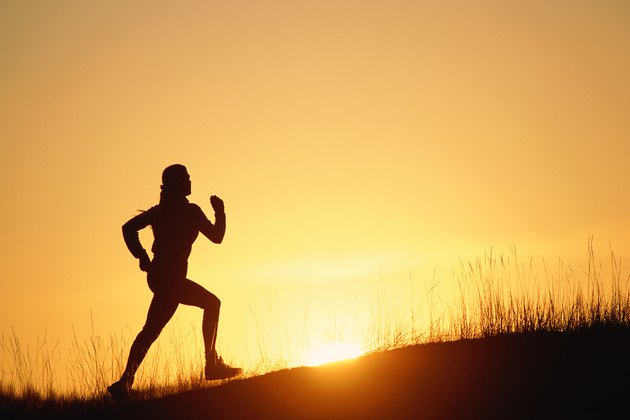 Silhouette of person running up hill