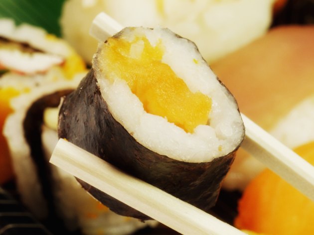 A sushi roll held with a pair of chopsticks