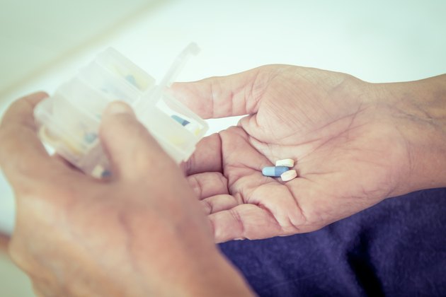 old woman hand pouring pills from a pill reminder box