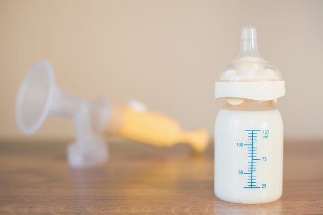 Manual breast pump and milk at background