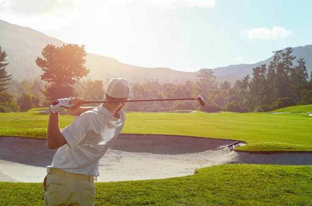 golf man takes a swing over bunker