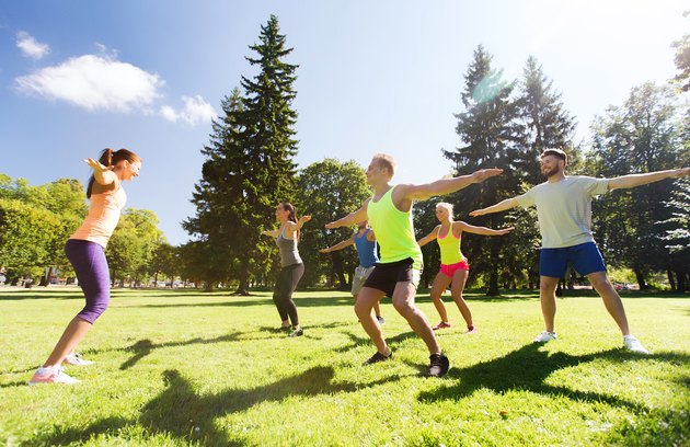 group of happy friends exercising outdoors