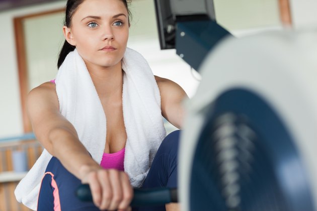 Woman working out on row machine in fitness studio
