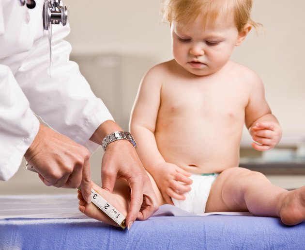 Doctor giving baby girl checkup on an examination table