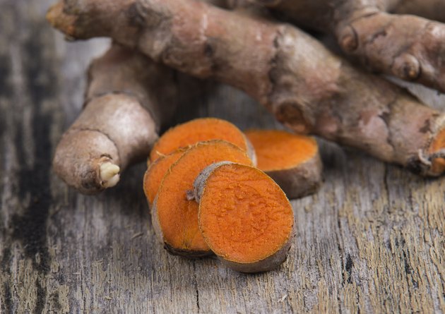 pile of fresh turmeric roots on wooden