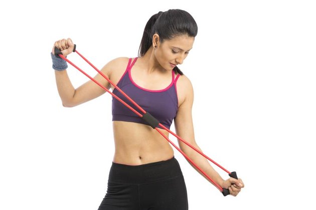 Young Indian girl doing exercise with rubber resistance band. isolated on white.