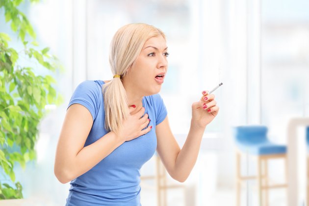 Young woman coughing from a cigarette
