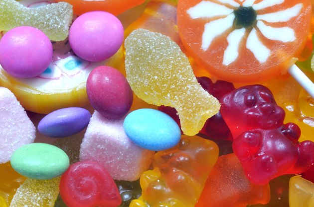 Lollipop, gummy bears and sour candy on colored smarties