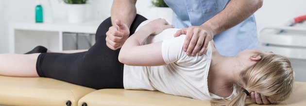 Physiotherapist is rehabilitating young woman back in medical office