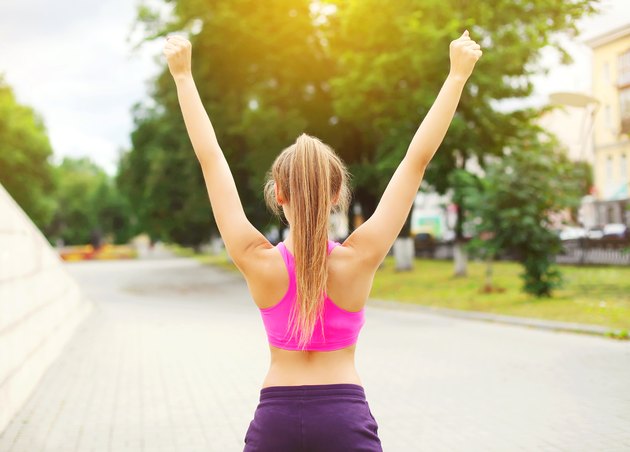 Fitness happy runner woman enjoying after training in city park,
