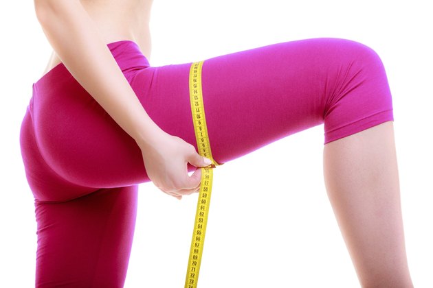 Fitness woman fit girl with measure tape measuring her thigh