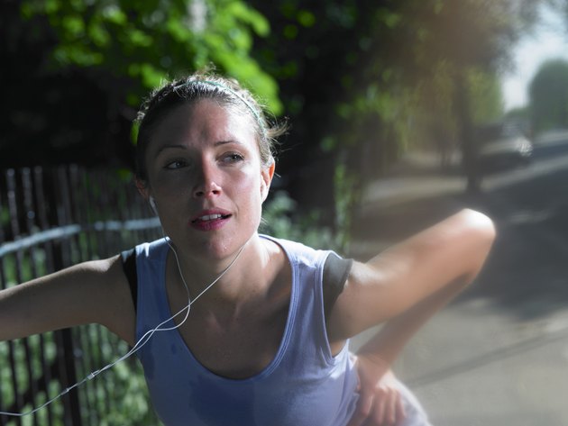 Young woman stretching by fence on street