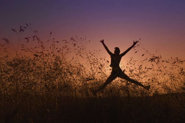 silhouette of girl jumping in a meadow