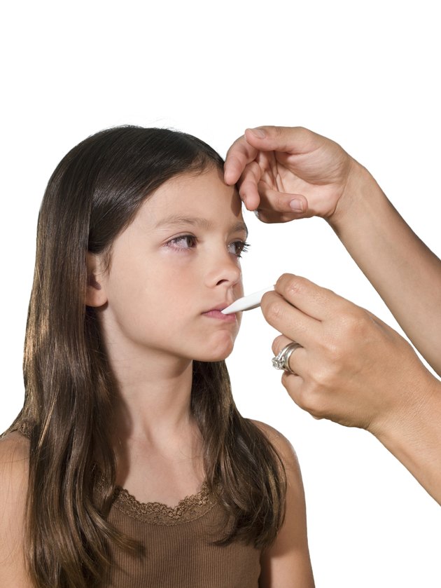 Girl (6-7) getting temperature taken by woman indoors
