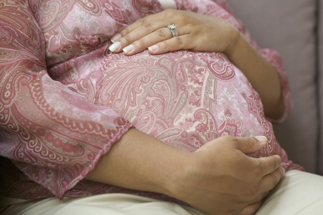 Mid section of African American holding pregnant belly