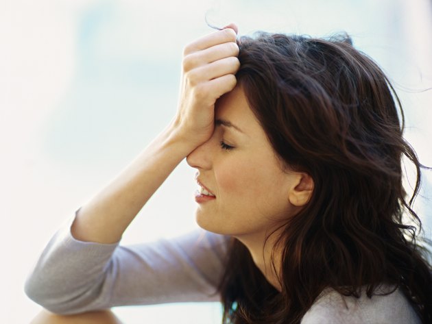 side profile of a young woman holding her head in her hand