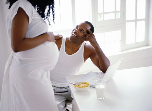 side profile of a pregnant woman standing and talking to her husband