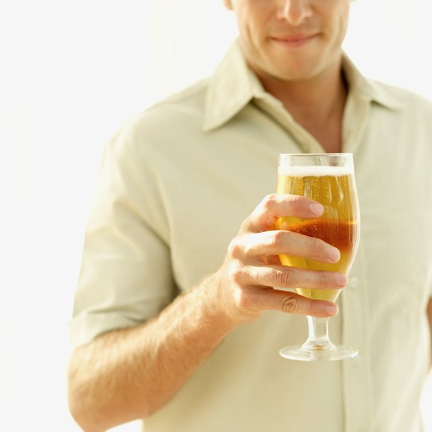 mid section view of a mid adult man holding a glass of beer