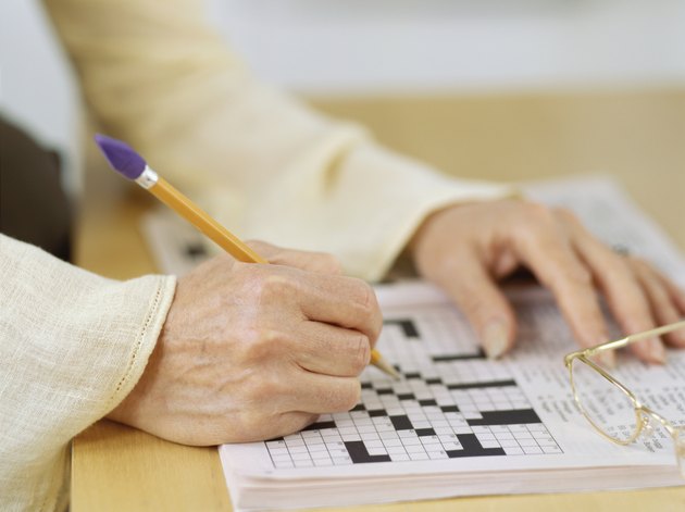 close-up of a human hand doing a crossword puzzle