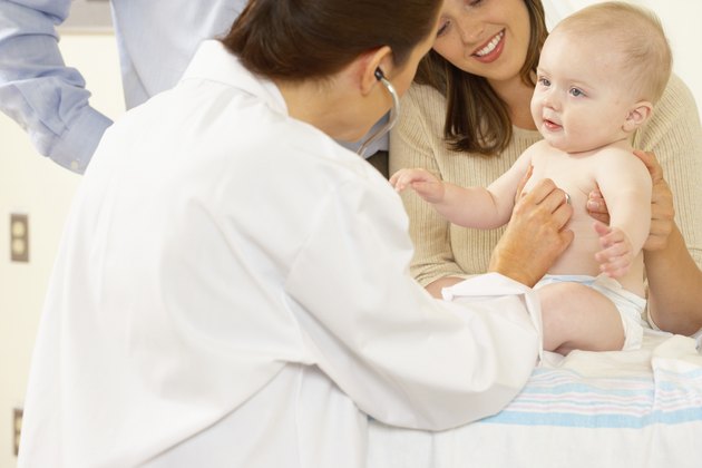 Side profile of a female doctor examining a baby boy with a stethoscope