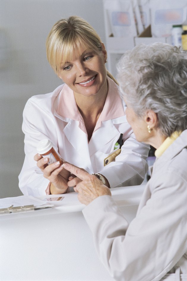Woman and pharmacist looking at bottle of prescription medicine