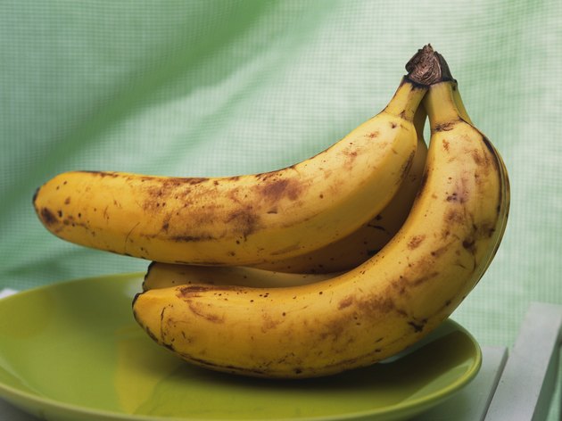 Bunch of bananas on green plate, side view