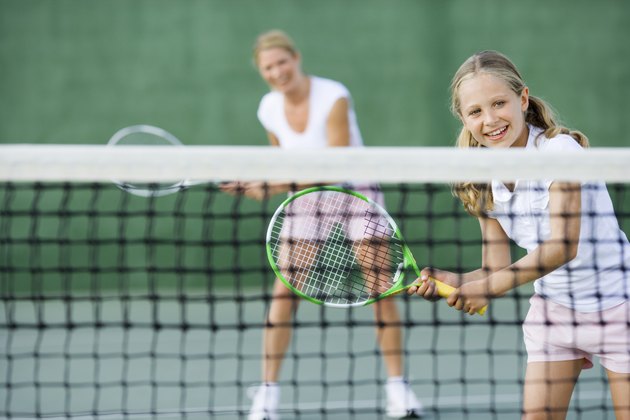 Girl playing tennis with parent