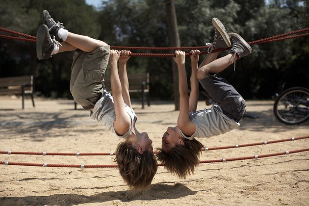 twins hang from structure in park
