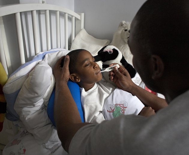 Father checking son's temperature with thermometer, elevated view