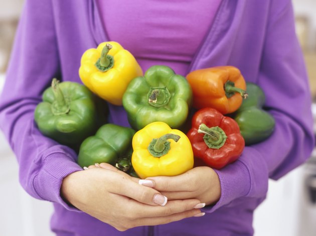 mid section view of a young woman holding assorted bell peppers