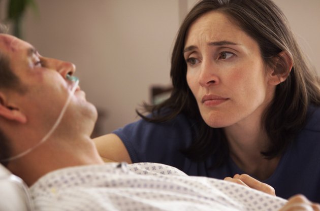 lifestyle photo of a caucasian woman at the hospital bedside of her injured husband