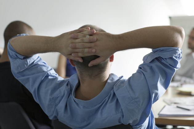 man leans back in office meeting