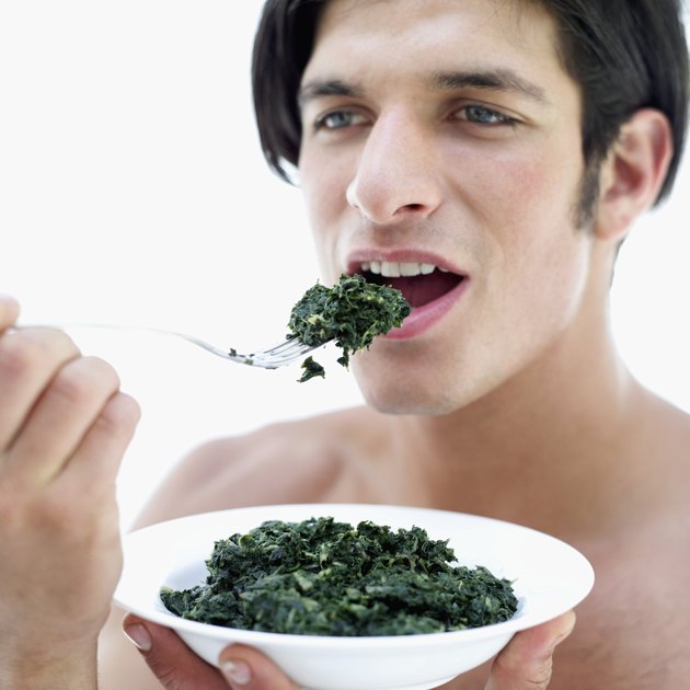 Portrait of a young man eating spinach with fork