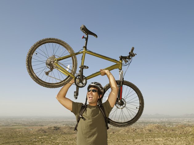 Hispanic man holding bicycle over head