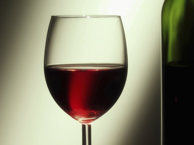 Glass of red wine besides wine bottle