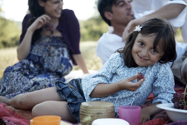 girl eating grape, family behind