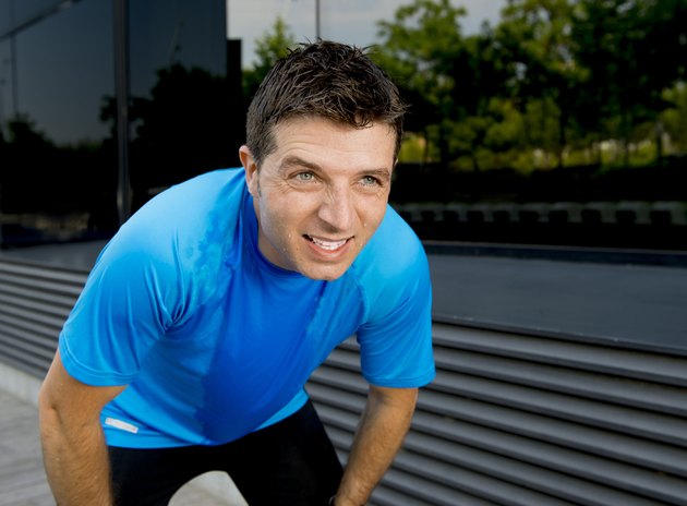 young attractive man leaning exhausted after running session sweating