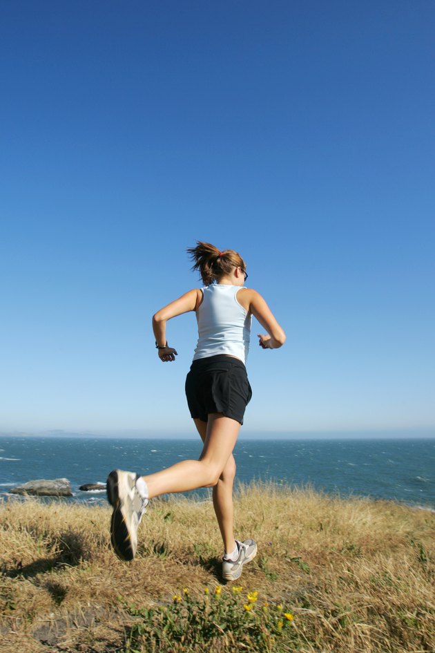 Woman running beside coastline, California, USA