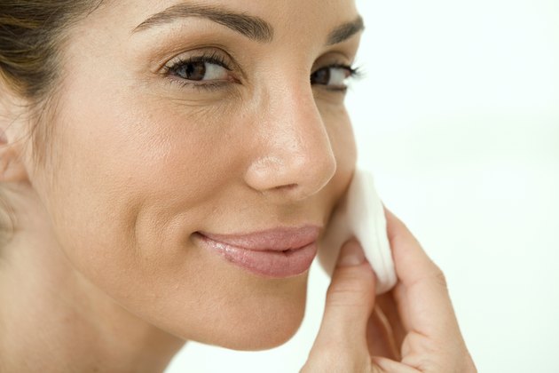 Close-up of a mid adult woman wiping her face with a cotton pad