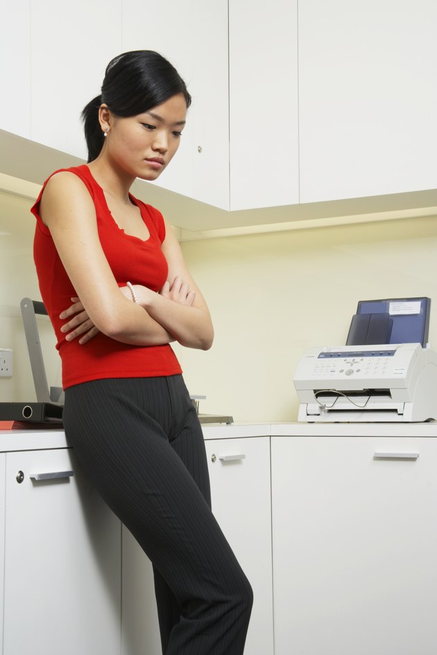 "Office worker leaning against counter, looking down, three quarter length"