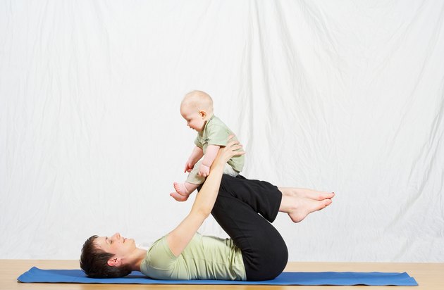 Reclining mother balancing baby on her knees