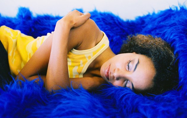 Close-up of a young woman sleeping on a blue furry rug