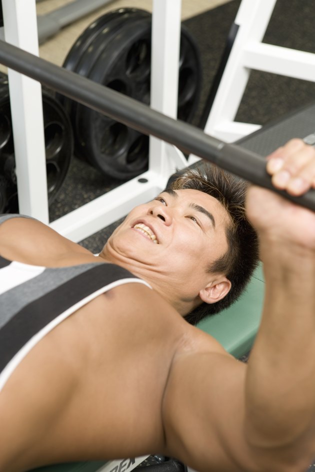 Man lifting barbell in gym, high angle view, differential focus