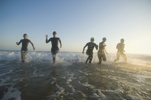 Multi-ethnic swimmers running in surf
