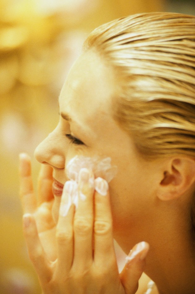 Close-up of a young woman applying moisturizer on her face