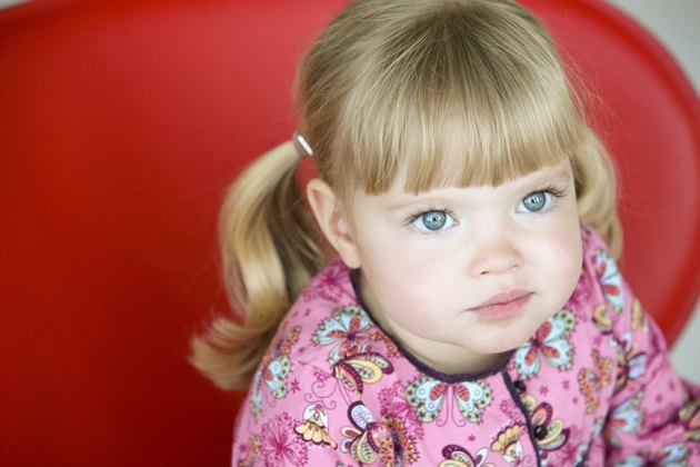 Little girl sitting on a red chair