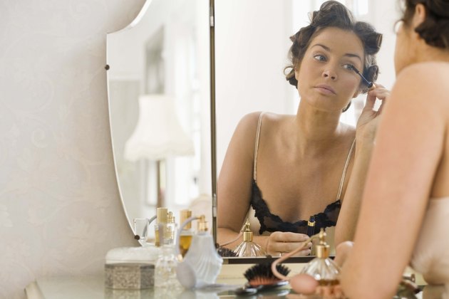 Woman applying makeup in mirror