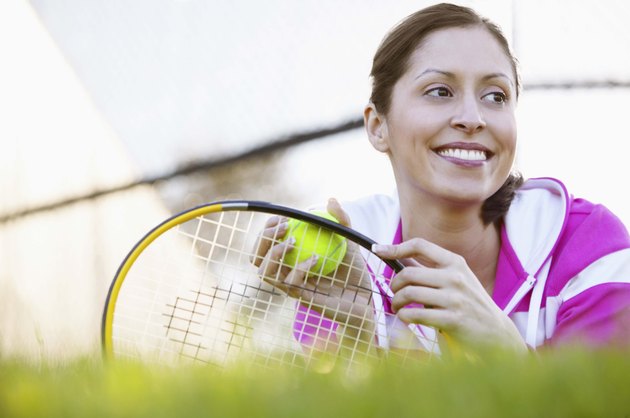 Woman with tennis equipment on grass