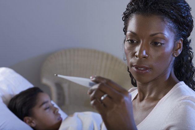 Mother reading thermometer reading with sick daughter